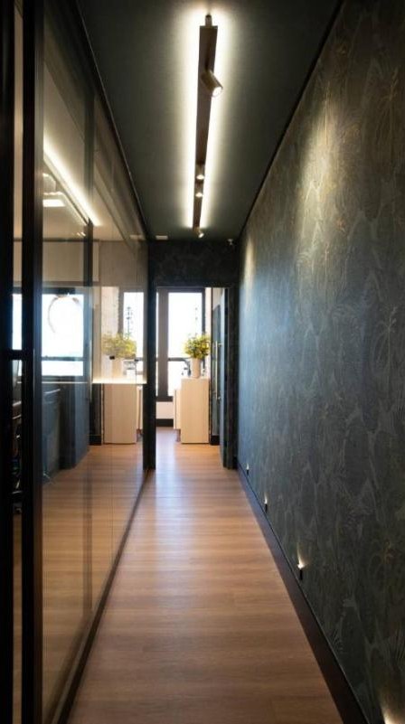 Corredor com trilho de luz no teto e balizadores no rodapé